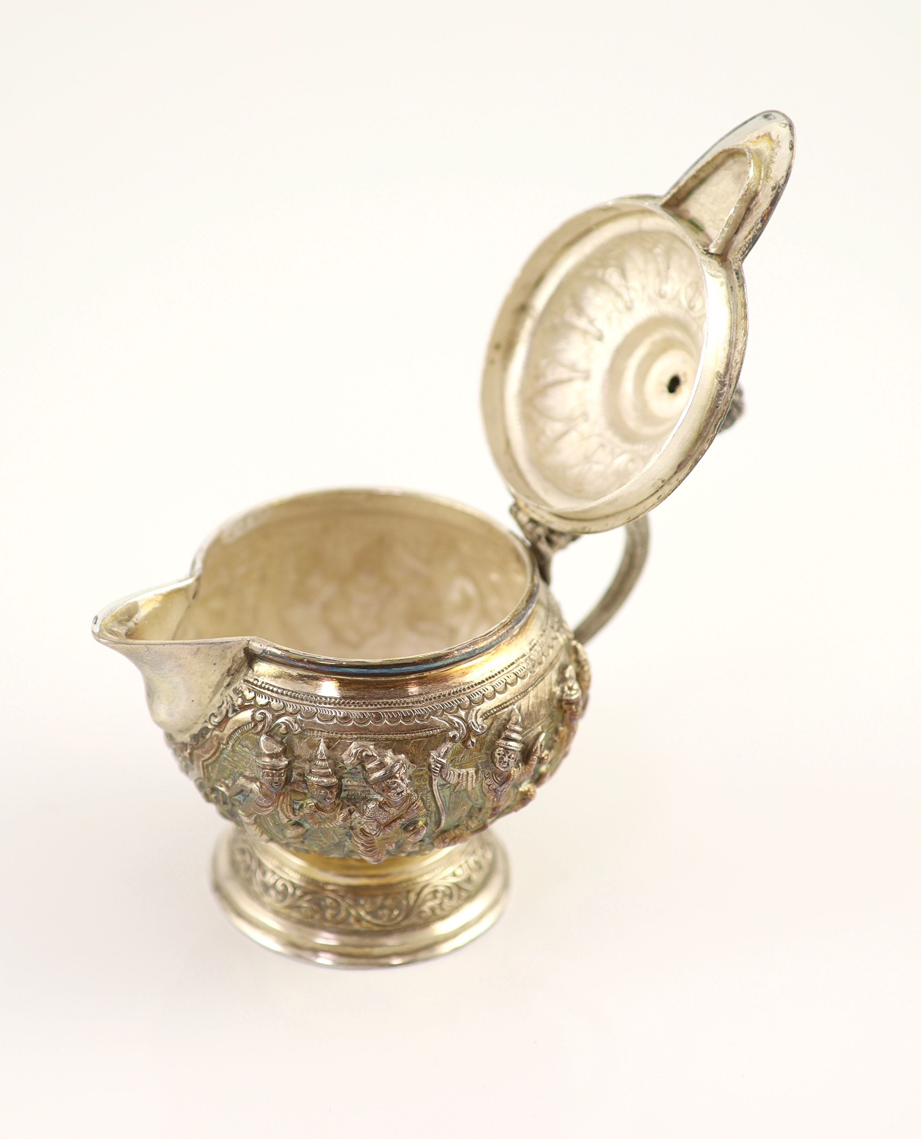 An impressive Burmese Sterling silver (950) three-piece tea service, with tray, cast with figures, teapot with cockerel spout and figural handle